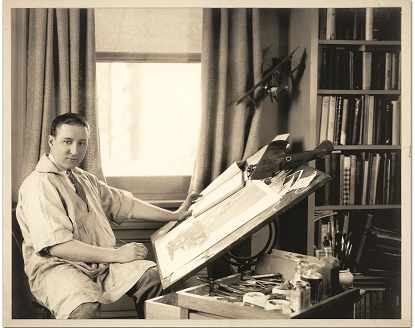 An artist at his drawing table working on an aviation illustration